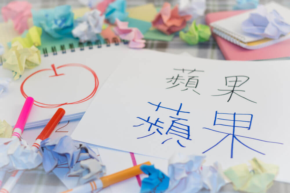 Image of a notebook with an apple drawn in red marker and Chinese Kanji on a separate piece of paper